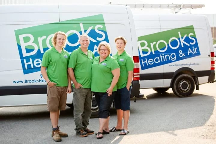 The Brooks family standing in front of their Brooks Heating & Air vans